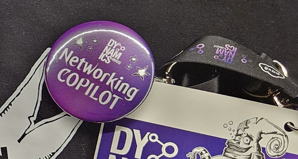 Close-up of Dynamics Minds networking materials and purple Networking Copilot badge.